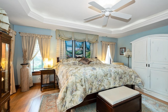 bedroom with a raised ceiling, light hardwood / wood-style flooring, ceiling fan, ornamental molding, and a closet