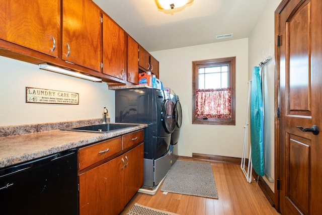 washroom featuring cabinets, light wood-type flooring, washer and clothes dryer, and sink