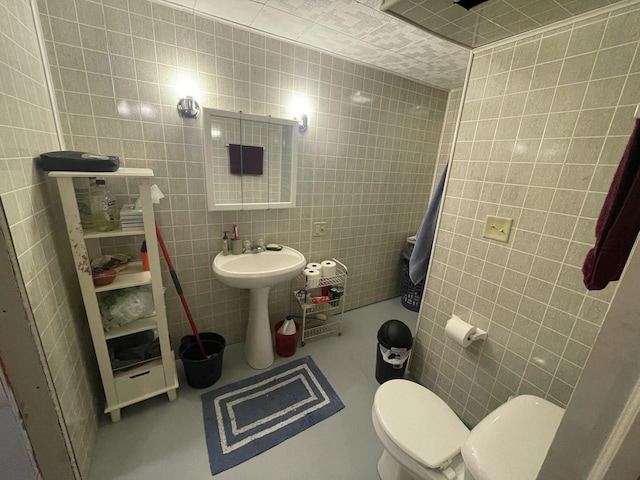 bathroom with tile walls and toilet