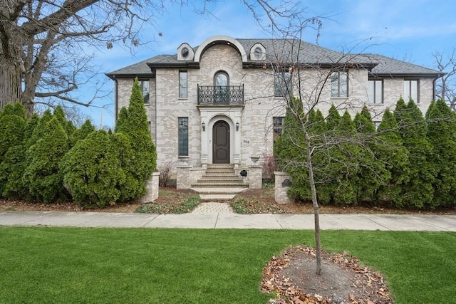 french provincial home with a balcony and a front yard