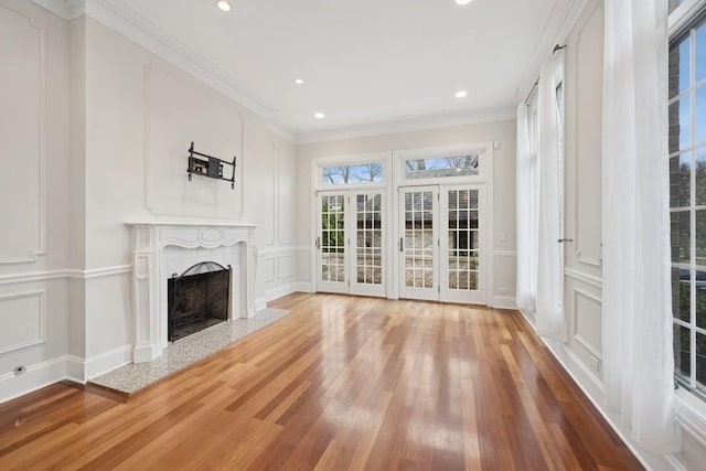 unfurnished living room with hardwood / wood-style floors and crown molding