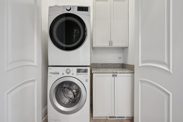 laundry area featuring cabinets and stacked washer and dryer