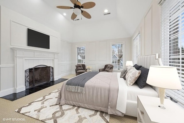 bedroom featuring a tile fireplace, vaulted ceiling, and ceiling fan