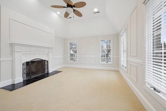 unfurnished living room featuring dark colored carpet, ceiling fan, lofted ceiling, and a tile fireplace