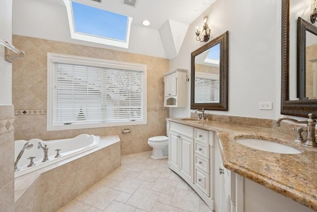 bathroom with a skylight, tiled tub, toilet, vanity, and tile walls