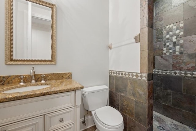 bathroom featuring tiled shower, vanity, and toilet