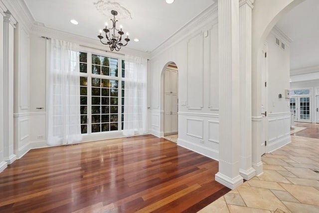 unfurnished dining area featuring a chandelier, wood-type flooring, and crown molding