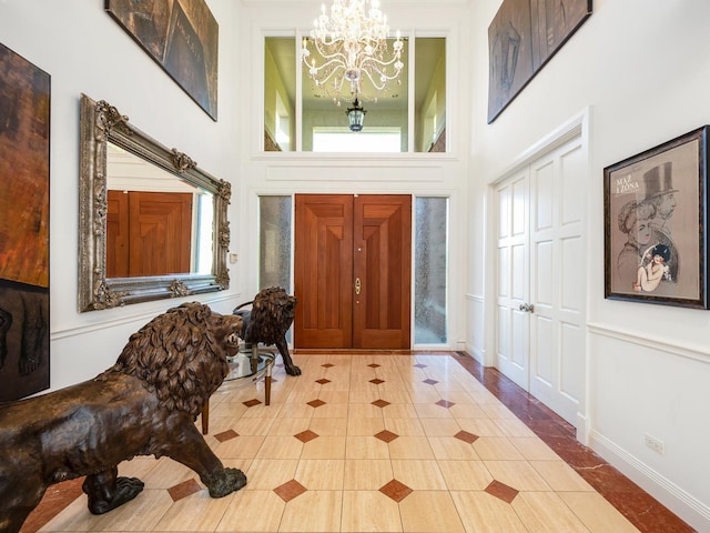 entryway featuring a chandelier, light tile patterned floors, a towering ceiling, and a healthy amount of sunlight