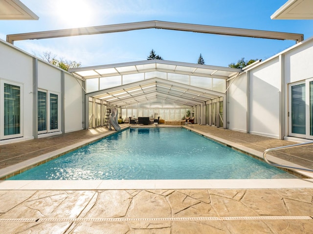 view of swimming pool featuring glass enclosure and a patio