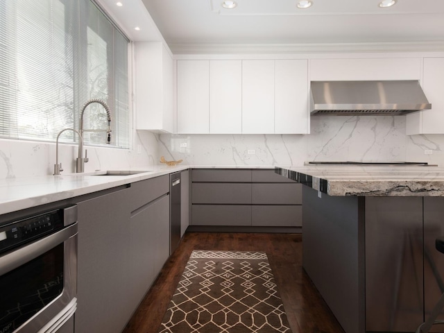 kitchen featuring gray cabinetry, stainless steel oven, exhaust hood, sink, and white cabinetry