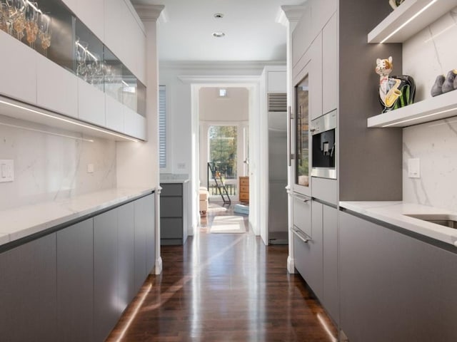 kitchen featuring ornamental molding, light stone counters, tasteful backsplash, dark hardwood / wood-style flooring, and white cabinetry