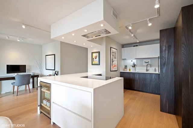 kitchen with a center island, wine cooler, black electric cooktop, white cabinets, and light wood-type flooring