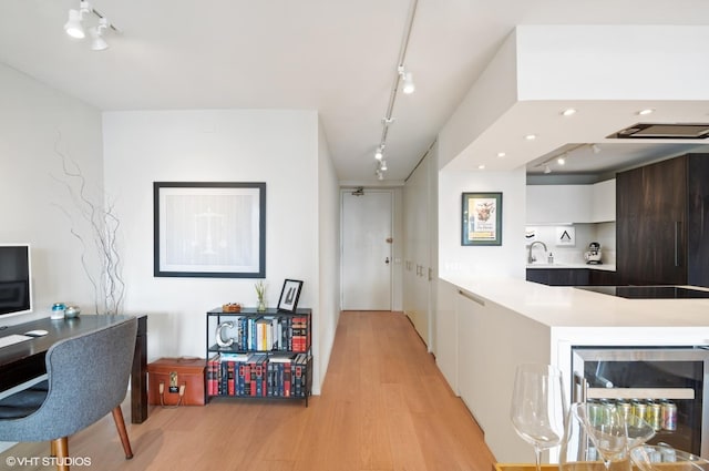 interior space featuring sink, beverage cooler, light hardwood / wood-style floors, and track lighting