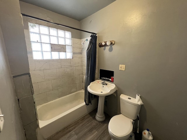 bathroom with hardwood / wood-style floors, toilet, and shower / bathtub combination with curtain