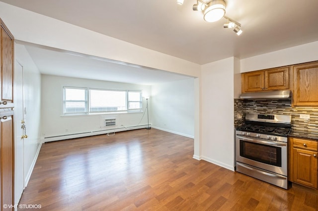 kitchen featuring stainless steel gas stove, a baseboard radiator, wood-type flooring, and backsplash