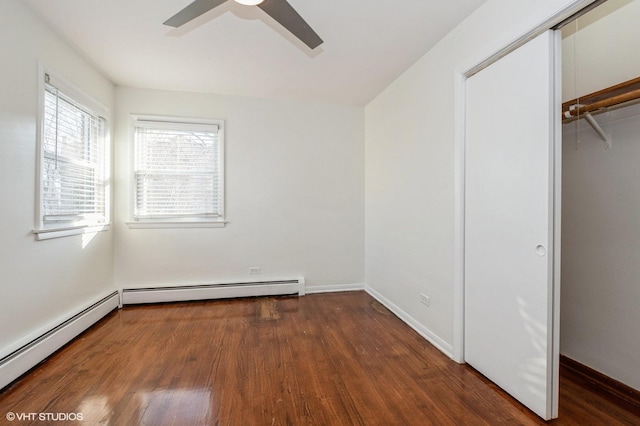 unfurnished bedroom featuring dark hardwood / wood-style flooring, a closet, baseboard heating, and ceiling fan