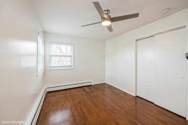 unfurnished bedroom featuring a closet, baseboard heating, ceiling fan, and dark wood-type flooring