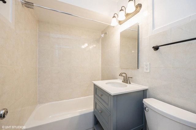 full bathroom with toilet, vanity, tile walls, and  shower combination