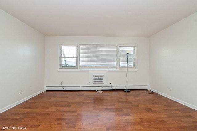 empty room featuring a wall mounted AC, a baseboard radiator, and hardwood / wood-style flooring