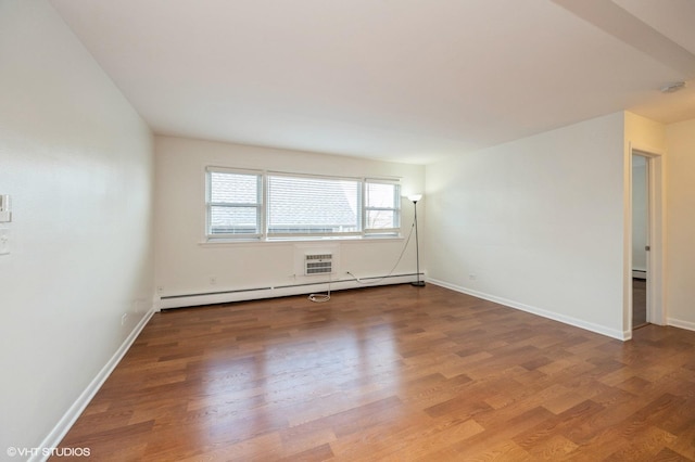 empty room with baseboard heating and hardwood / wood-style flooring