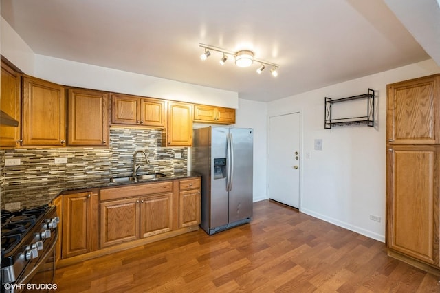 kitchen with dark stone countertops, appliances with stainless steel finishes, dark hardwood / wood-style flooring, sink, and backsplash