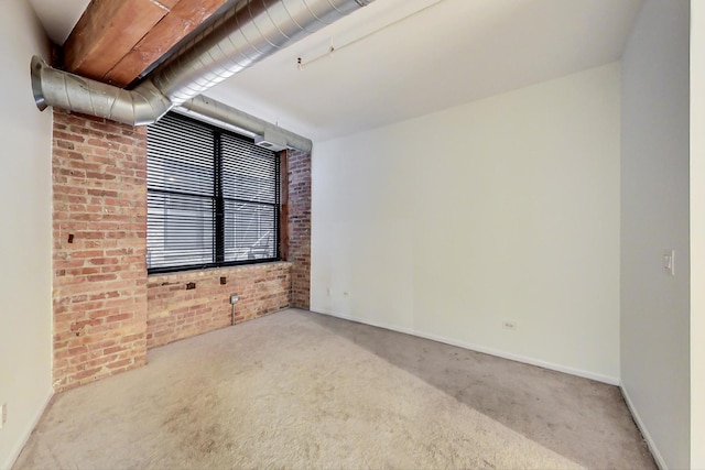 empty room featuring light carpet and brick wall