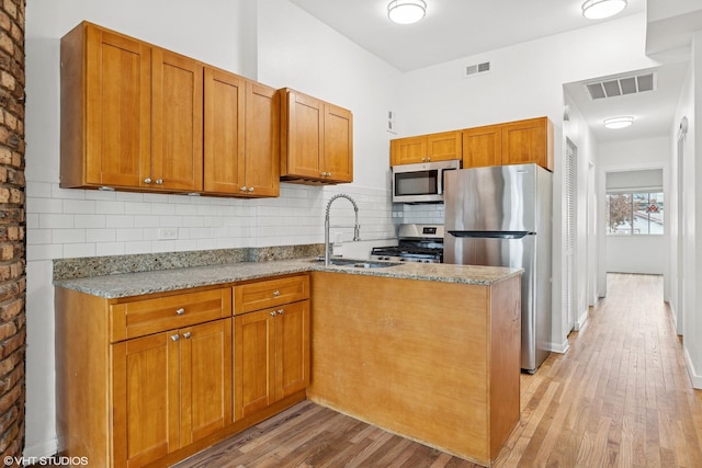 kitchen featuring appliances with stainless steel finishes, light wood finished floors, a sink, and visible vents