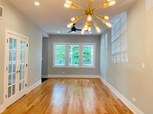 spare room featuring light hardwood / wood-style flooring, a chandelier, and french doors