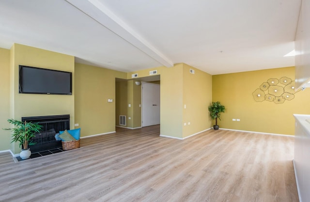 unfurnished living room with beam ceiling and light wood-type flooring