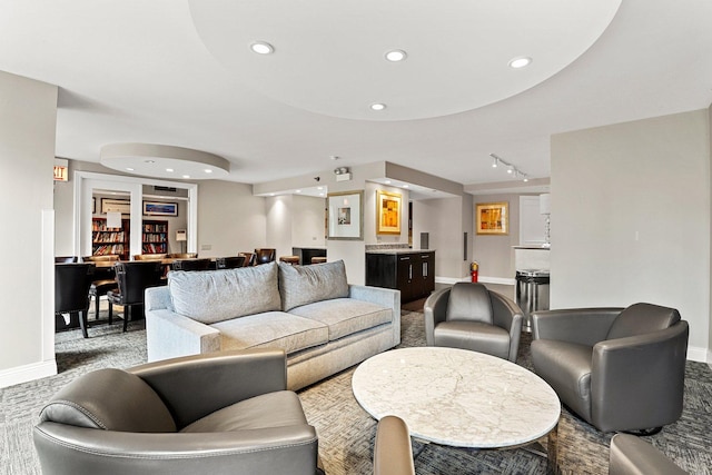 carpeted living room featuring bar area and track lighting