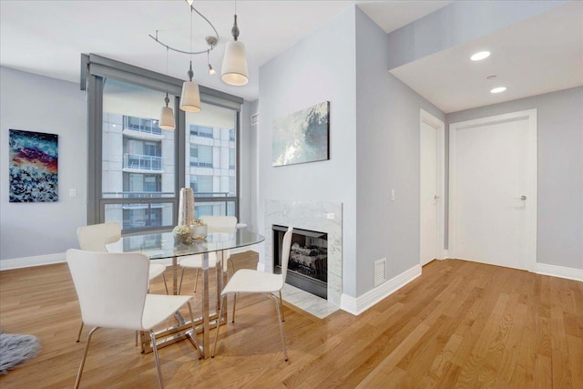 dining room with light hardwood / wood-style flooring and a high end fireplace