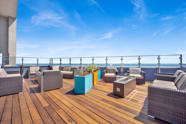 deck featuring a water view and an outdoor living space with a fire pit