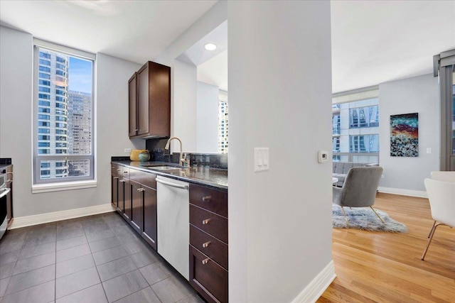 kitchen featuring dishwasher, dark brown cabinetry, tile patterned flooring, and sink