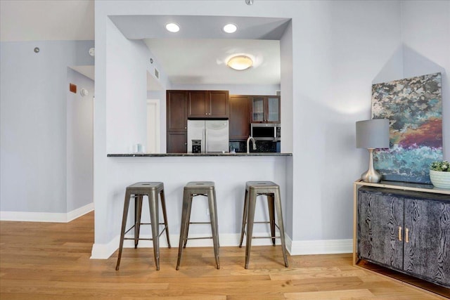 kitchen featuring a breakfast bar, light wood-type flooring, kitchen peninsula, and stainless steel appliances