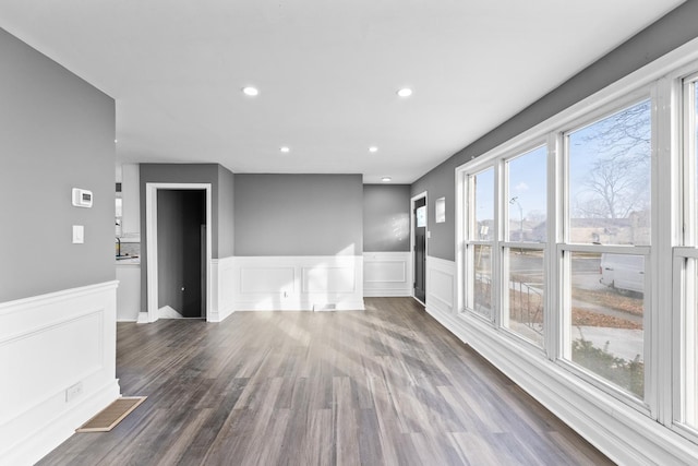 unfurnished room featuring a healthy amount of sunlight and dark wood-type flooring