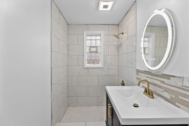 bathroom with tiled shower and vanity