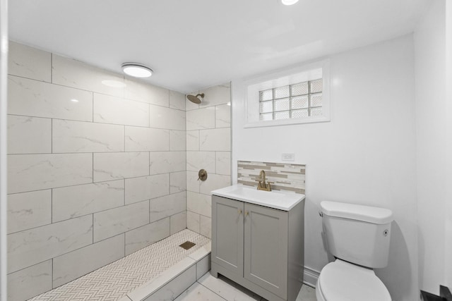 bathroom featuring decorative backsplash, a tile shower, vanity, and toilet