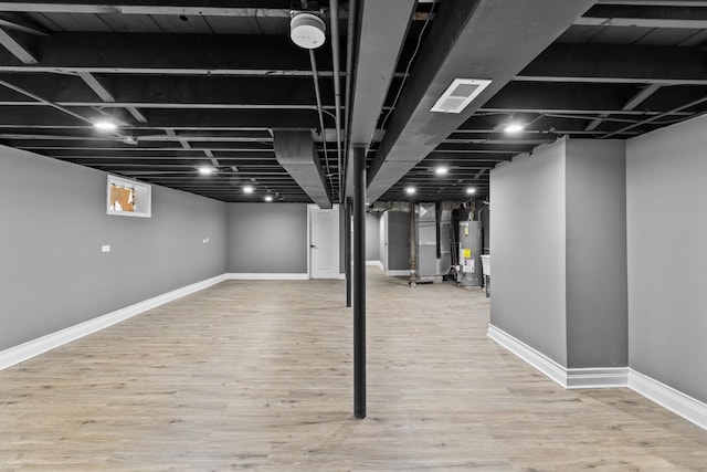 basement with heating unit, wood-type flooring, and gas water heater