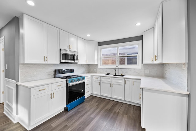 kitchen with sink, decorative backsplash, dark hardwood / wood-style flooring, white cabinetry, and range with gas cooktop