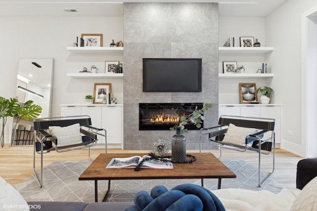 living room featuring a fireplace, hardwood / wood-style floors, and built in features