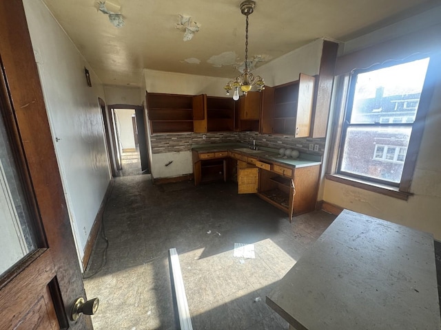 kitchen with backsplash, decorative light fixtures, sink, and a chandelier