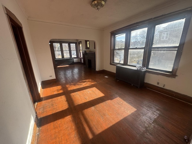 empty room featuring dark hardwood / wood-style floors, radiator, and a brick fireplace