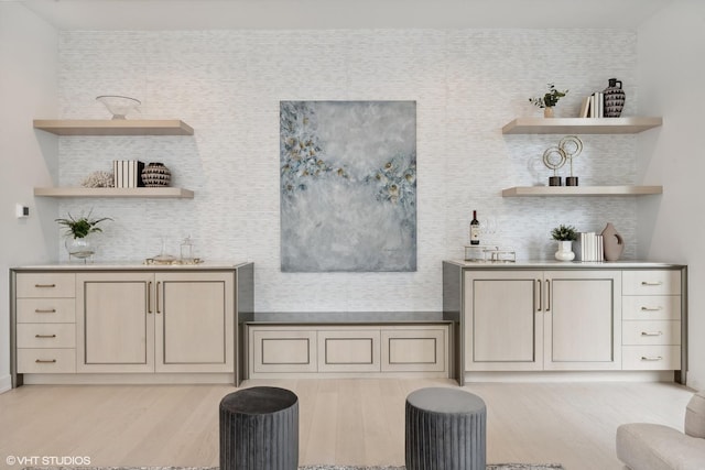 bar with decorative backsplash, light hardwood / wood-style flooring, and sink