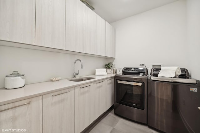 laundry area featuring washer and dryer, light tile patterned flooring, cabinets, and sink