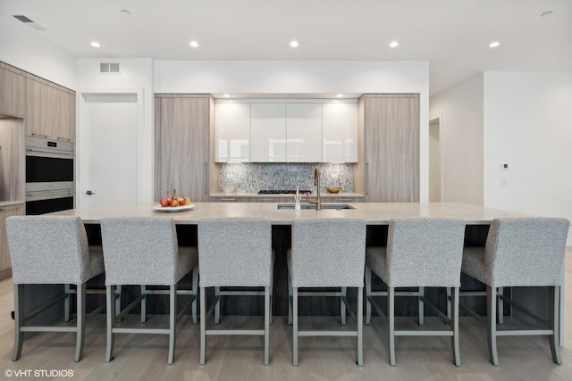 kitchen with a breakfast bar, a center island with sink, and sink