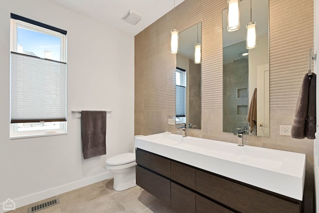 bathroom featuring tile patterned floors, vanity, tile walls, and toilet