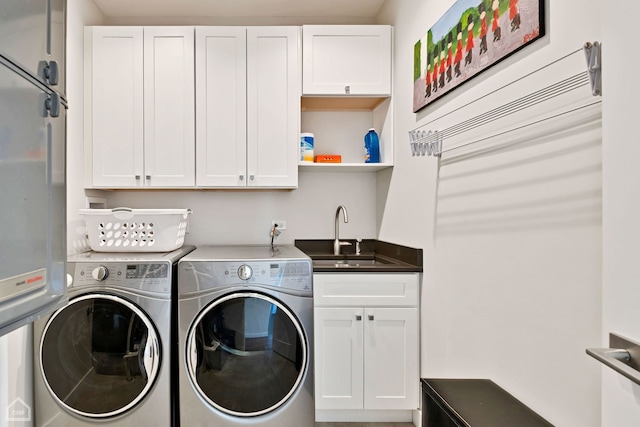 clothes washing area with cabinets, washing machine and dryer, and sink