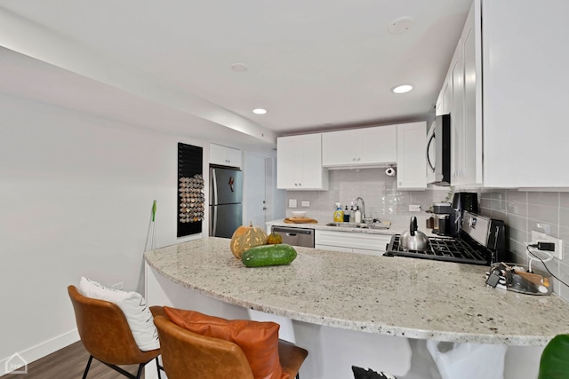 kitchen featuring a breakfast bar, sink, dark hardwood / wood-style flooring, white cabinetry, and stainless steel appliances