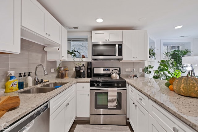 kitchen featuring white cabinets, stainless steel appliances, tasteful backsplash, and sink