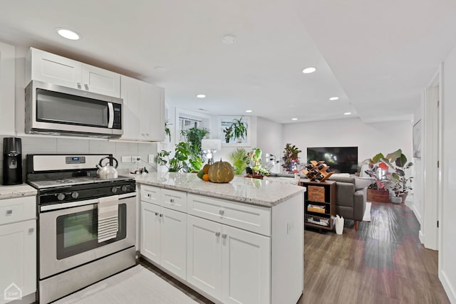 kitchen with decorative backsplash, kitchen peninsula, stainless steel appliances, and white cabinetry